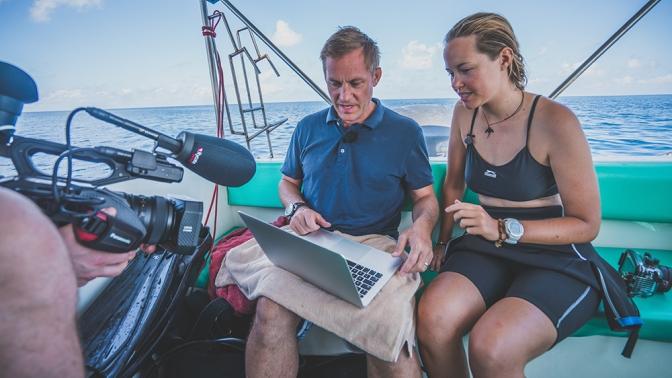 En person filmar två personer med en dator på en båt