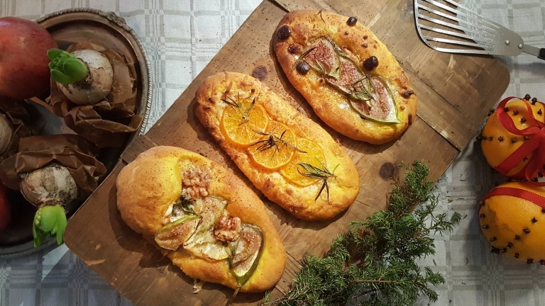 Tre små pizzor med olika fyllningar serverade på skärbräda av trä. 