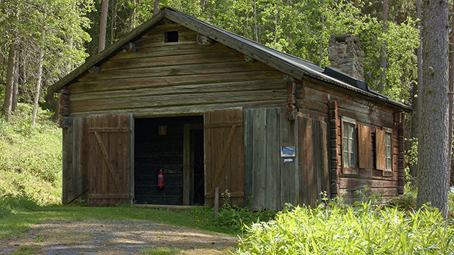 A smithy seen from a distance with a surrounding forest