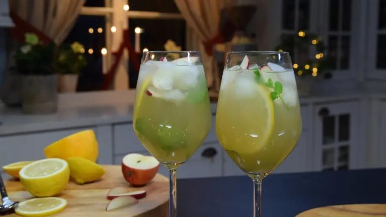 Två glas med gul-grön vätska, citronskiva, is och äpple.
