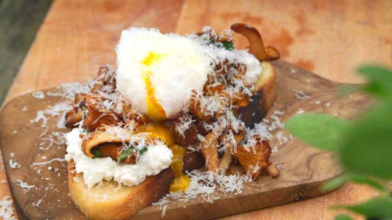 En macka med en kokt hel ägg på och topping med parmesanost på en trä skärbräda.