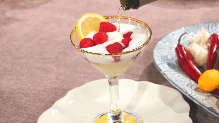 Ett Martiniglas med guldkant fylls med bubbel över en citronsorbet med hallon 