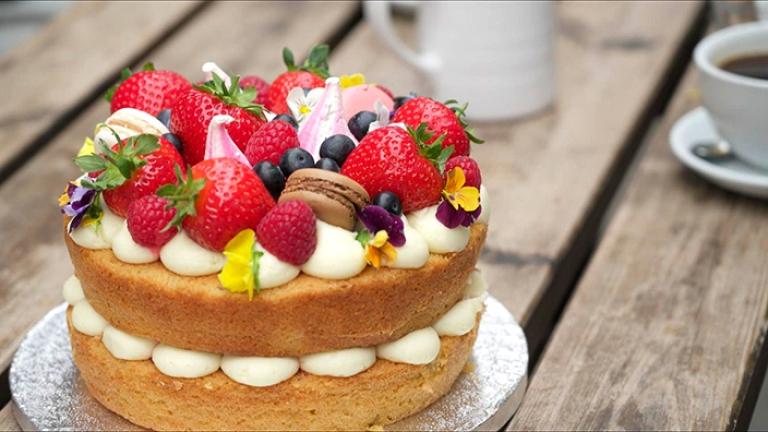 Sponge cake i lager med jordgubbar och blåbär på toppen.