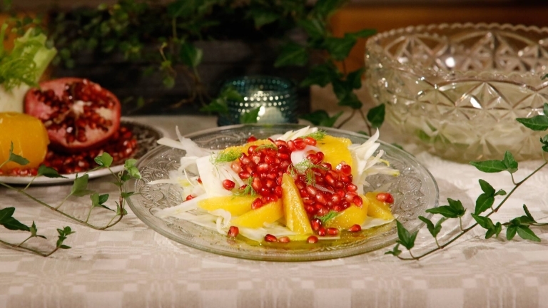 Fänkålssallad serverad på glasfat, dekorerad med fänkålsdill och granatäpplekärnor. 