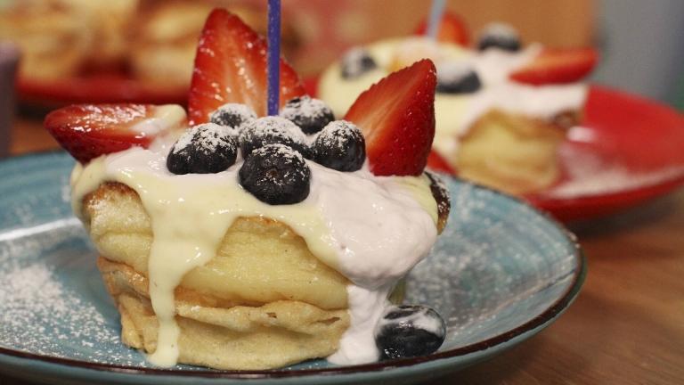 Muffinspannkaka på en tallrik, toppad med kvarg, blåbär, jordgubbar och florsocker.