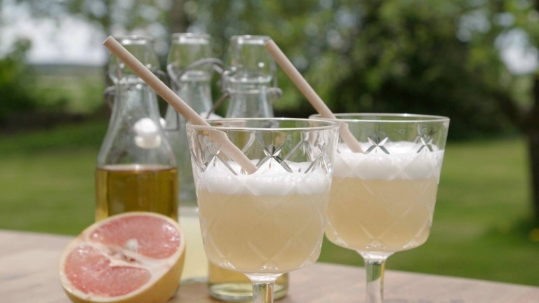Punschdrink Diki-diki i höga glas med sugrör och en grapefrukt i bakgrunden.