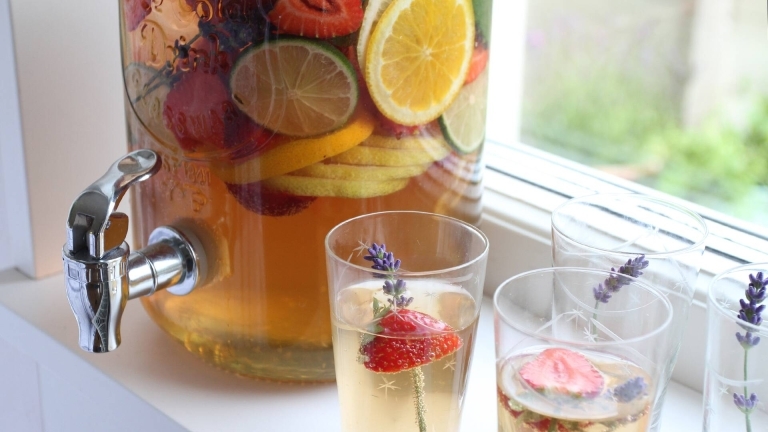glasbehållare med dryck med frukt och bär i, på fönsterbräda, några glas med dryck i.